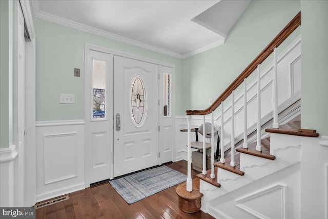 foyer entrance featuring visible vents, dark wood-type flooring, wainscoting, and crown molding