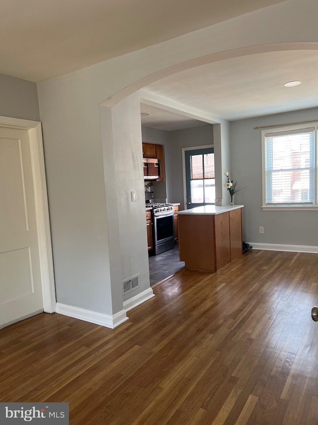 interior space featuring visible vents, dark wood finished floors, light countertops, arched walkways, and stainless steel appliances