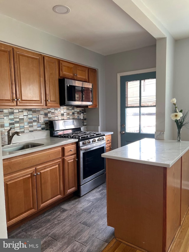 kitchen with a sink, decorative backsplash, brown cabinets, and appliances with stainless steel finishes