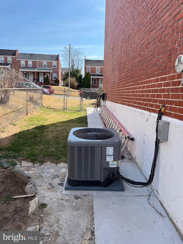 exterior details with a gate, brick siding, central AC unit, and fence