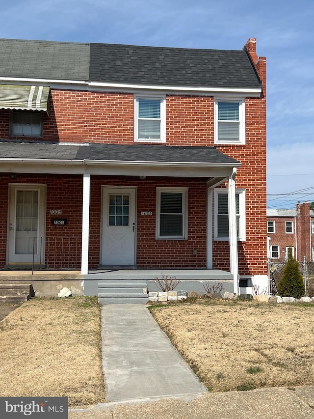 view of property with a porch, brick siding, and a shingled roof