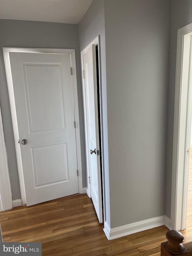 hallway featuring wood finished floors and baseboards