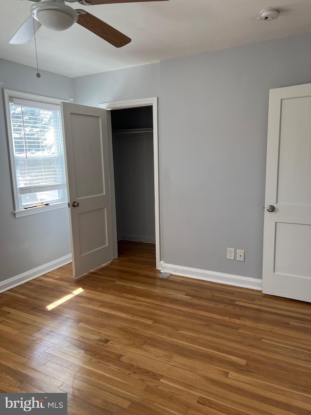 unfurnished bedroom with a closet, ceiling fan, baseboards, and wood finished floors