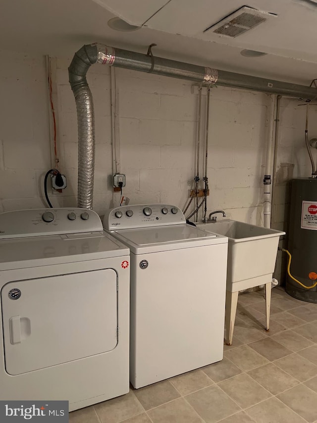 clothes washing area with washer and dryer, laundry area, visible vents, and water heater