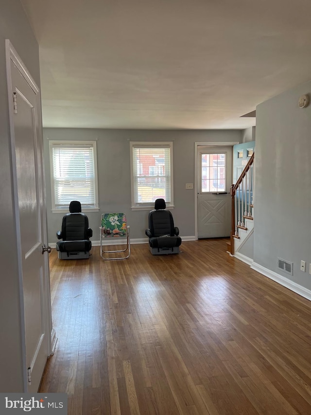 unfurnished room featuring visible vents, baseboards, wood finished floors, and stairs