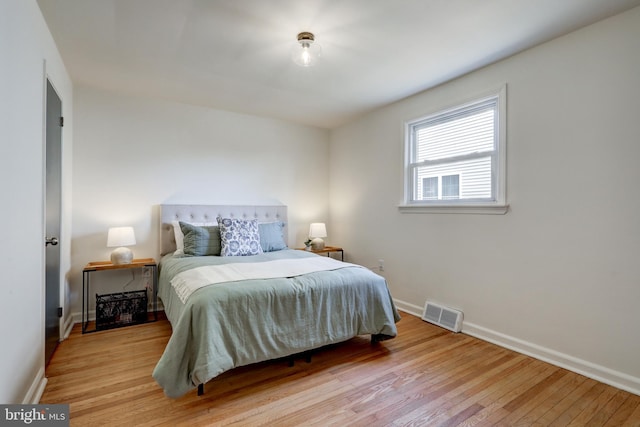 bedroom with visible vents, baseboards, and hardwood / wood-style flooring