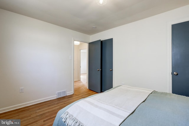 bedroom featuring visible vents, baseboards, and wood finished floors