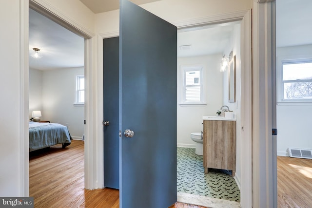 bathroom featuring visible vents, baseboards, toilet, wood finished floors, and vanity