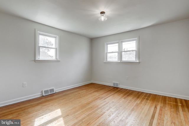 spare room featuring visible vents, baseboards, and hardwood / wood-style floors