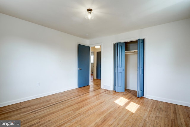 unfurnished bedroom with a closet, baseboards, and light wood-style flooring