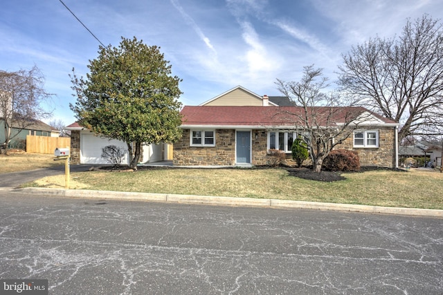 single story home with a front lawn, fence, driveway, stone siding, and an attached garage