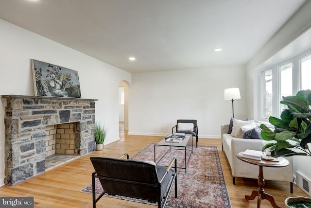 living area featuring visible vents, wood finished floors, recessed lighting, arched walkways, and baseboards