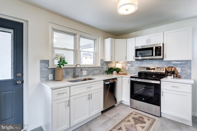 kitchen featuring light countertops, decorative backsplash, appliances with stainless steel finishes, white cabinetry, and a sink