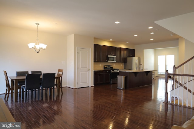 kitchen with a breakfast bar area, dark wood finished floors, light countertops, appliances with stainless steel finishes, and a chandelier