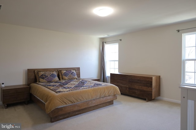 carpeted bedroom featuring multiple windows and baseboards