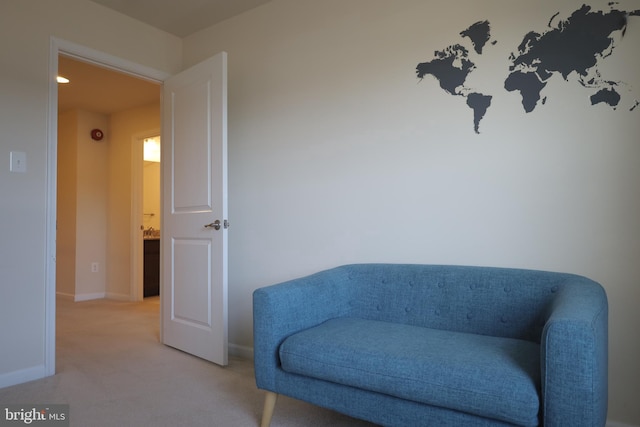 sitting room with baseboards and light carpet