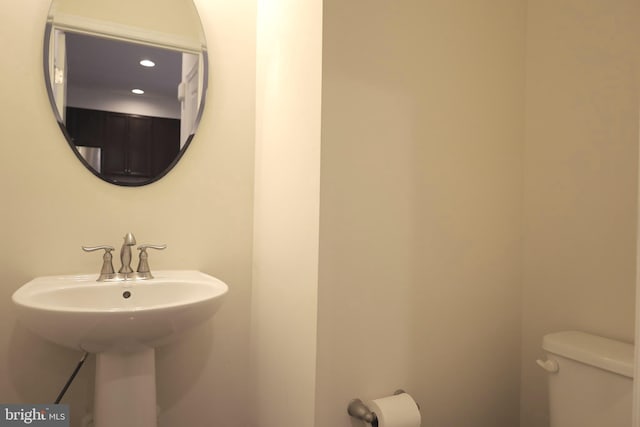 bathroom with toilet, recessed lighting, and a sink