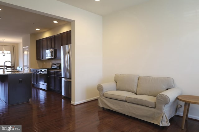 interior space with dark brown cabinets, dark wood-type flooring, a chandelier, open floor plan, and appliances with stainless steel finishes