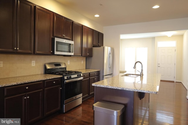 kitchen featuring dark wood finished floors, recessed lighting, a sink, stainless steel appliances, and backsplash