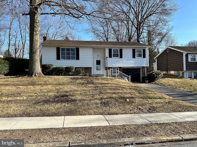 split foyer home featuring brick siding, driveway, a chimney, and a garage