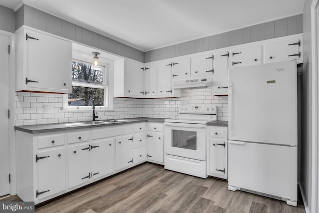 kitchen featuring dark wood finished floors, white appliances, dark countertops, and under cabinet range hood