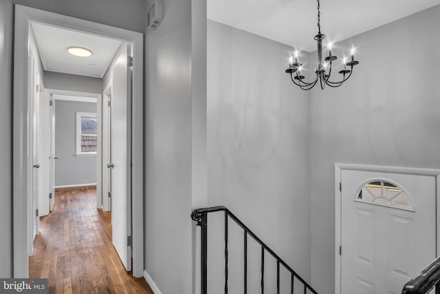 interior space with an inviting chandelier, hardwood / wood-style flooring, and baseboards