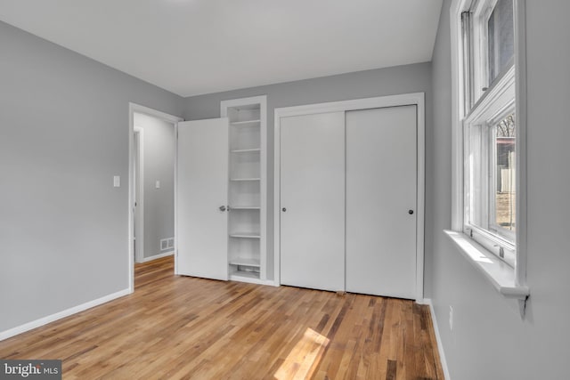 unfurnished bedroom featuring visible vents, wood finished floors, baseboards, and a closet