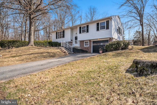 split foyer home featuring a garage, a front yard, brick siding, and driveway