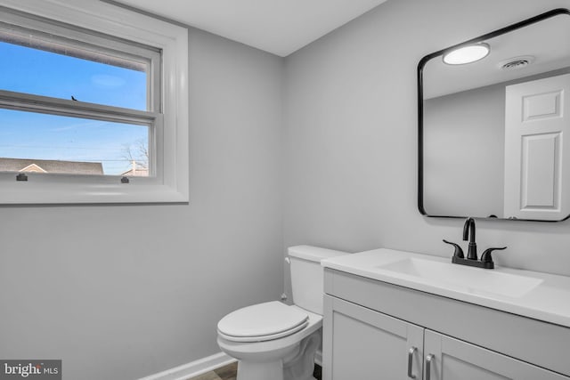 bathroom featuring visible vents, baseboards, toilet, wood finished floors, and vanity