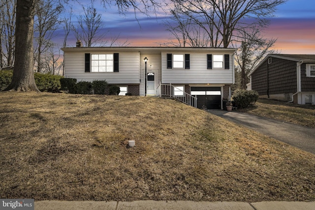 bi-level home featuring a garage, brick siding, and driveway