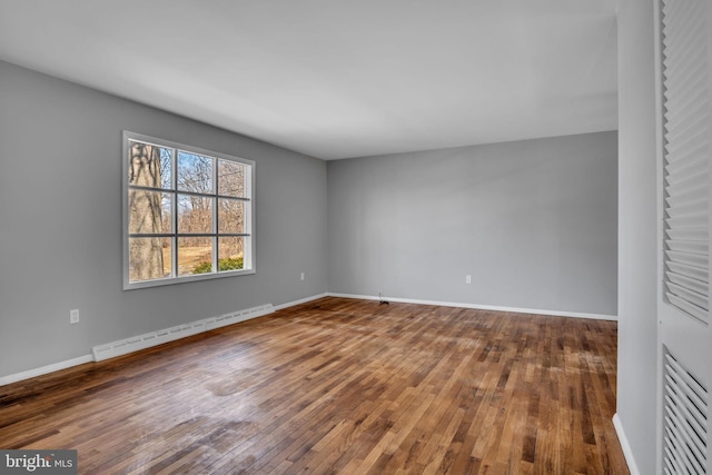 unfurnished room featuring baseboards, baseboard heating, and hardwood / wood-style floors