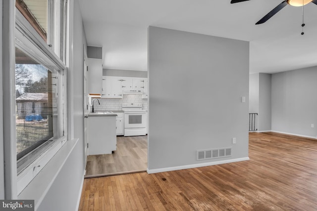 kitchen featuring light wood-type flooring, visible vents, electric stove, white cabinetry, and decorative backsplash