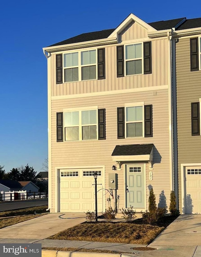 townhome / multi-family property with board and batten siding, concrete driveway, and a garage