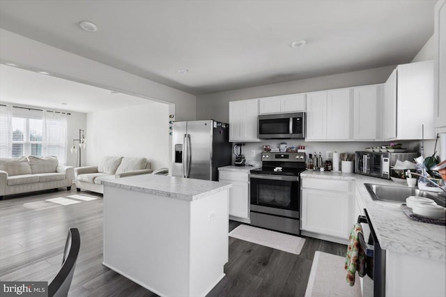 kitchen with stainless steel appliances, dark wood finished floors, white cabinets, and light countertops