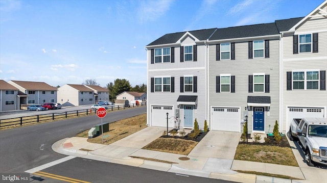 view of property featuring a garage, a residential view, and driveway