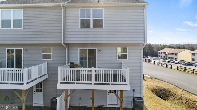 back of property featuring central AC and a shingled roof