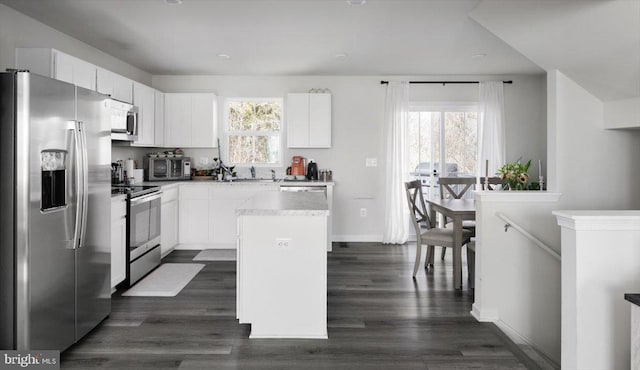 kitchen with white cabinetry, dark wood-style floors, appliances with stainless steel finishes, and a center island