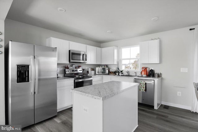 kitchen with a kitchen island, appliances with stainless steel finishes, white cabinets, and dark wood finished floors