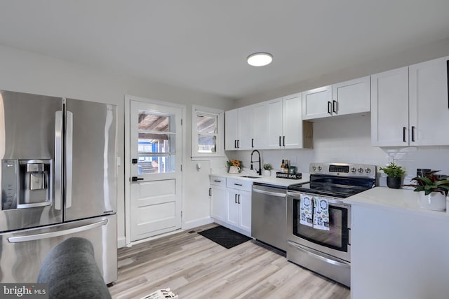 kitchen featuring a sink, stainless steel appliances, white cabinets, and light countertops