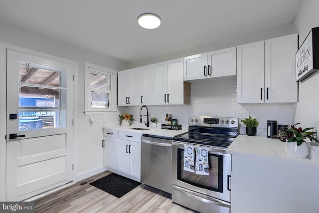 kitchen featuring light countertops, appliances with stainless steel finishes, light wood-style floors, white cabinetry, and a sink