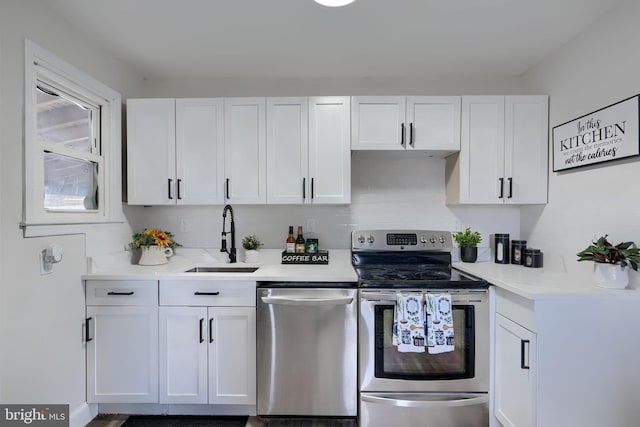 kitchen with a sink, stainless steel appliances, white cabinets, and light countertops