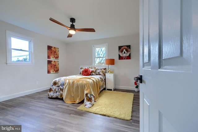 bedroom featuring ceiling fan, baseboards, and wood finished floors