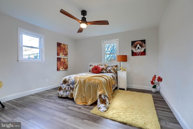 bedroom featuring baseboards, wood finished floors, and a ceiling fan