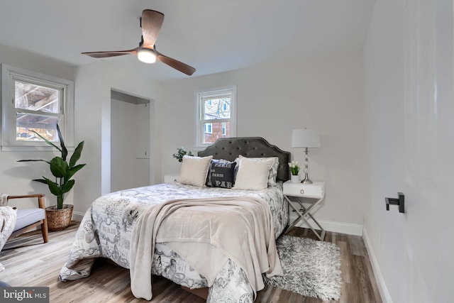 bedroom featuring ceiling fan, baseboards, and wood finished floors