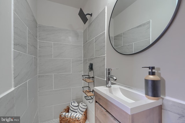 full bath featuring tiled shower and vanity