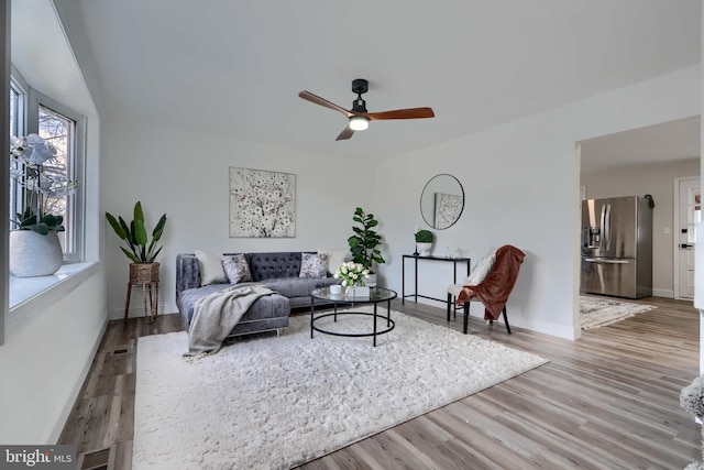 living area with visible vents, a ceiling fan, baseboards, and wood finished floors