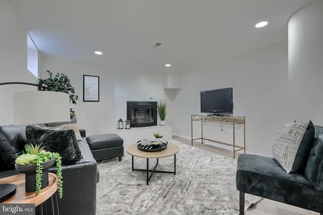 living room featuring recessed lighting, a brick fireplace, baseboards, and wood finished floors