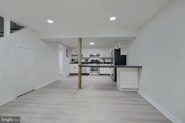 kitchen with dark countertops, baseboards, under cabinet range hood, white cabinets, and stainless steel appliances