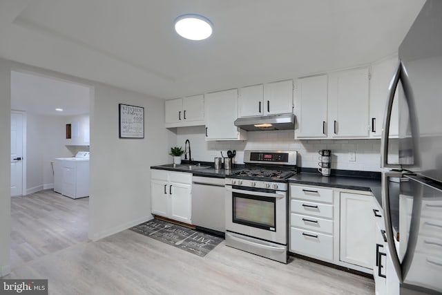 kitchen featuring washer and clothes dryer, under cabinet range hood, backsplash, dark countertops, and stainless steel appliances