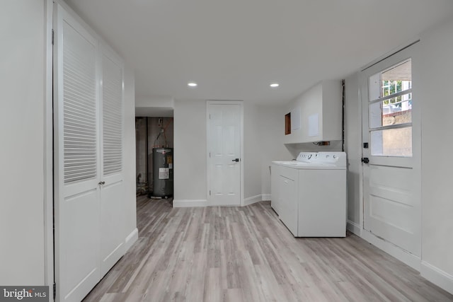 clothes washing area featuring light wood-type flooring, baseboards, electric water heater, and washing machine and clothes dryer